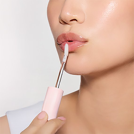 Close-up of a model applying ICD Glow-Up Lip Oil to her lips with the doe-foot applicator