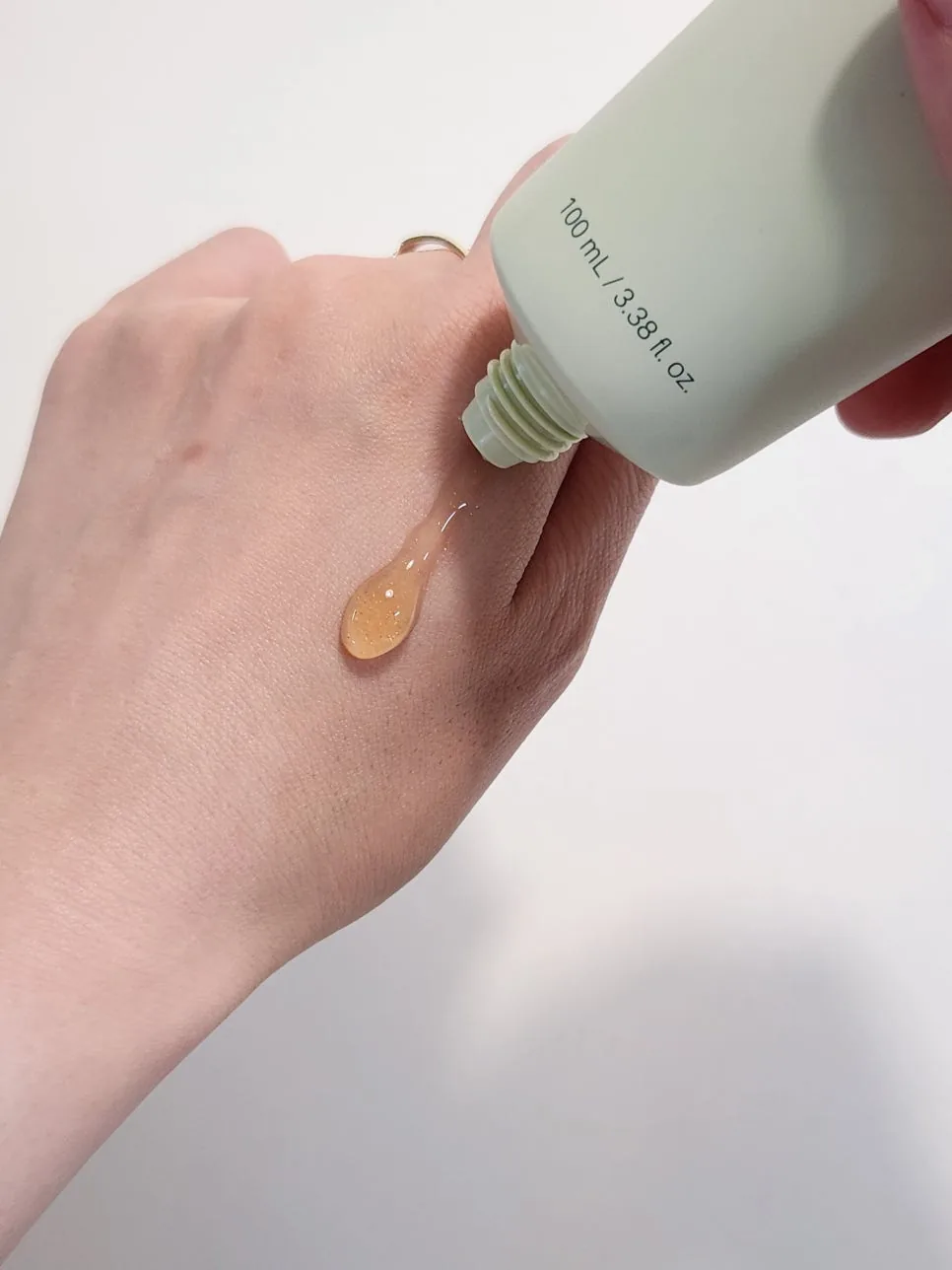 A drop of clear amber gel with tiny shimmering flecks squeezed onto the back of a hand from the green tube