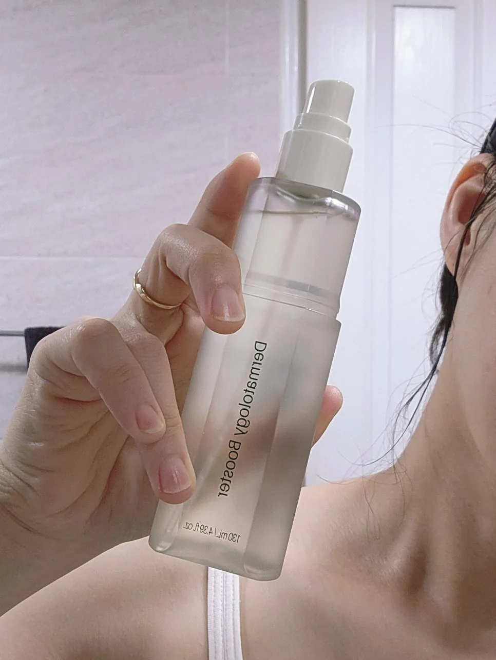 Dermatology Booster with its mist nozzle held up near the neck, ready to spray
