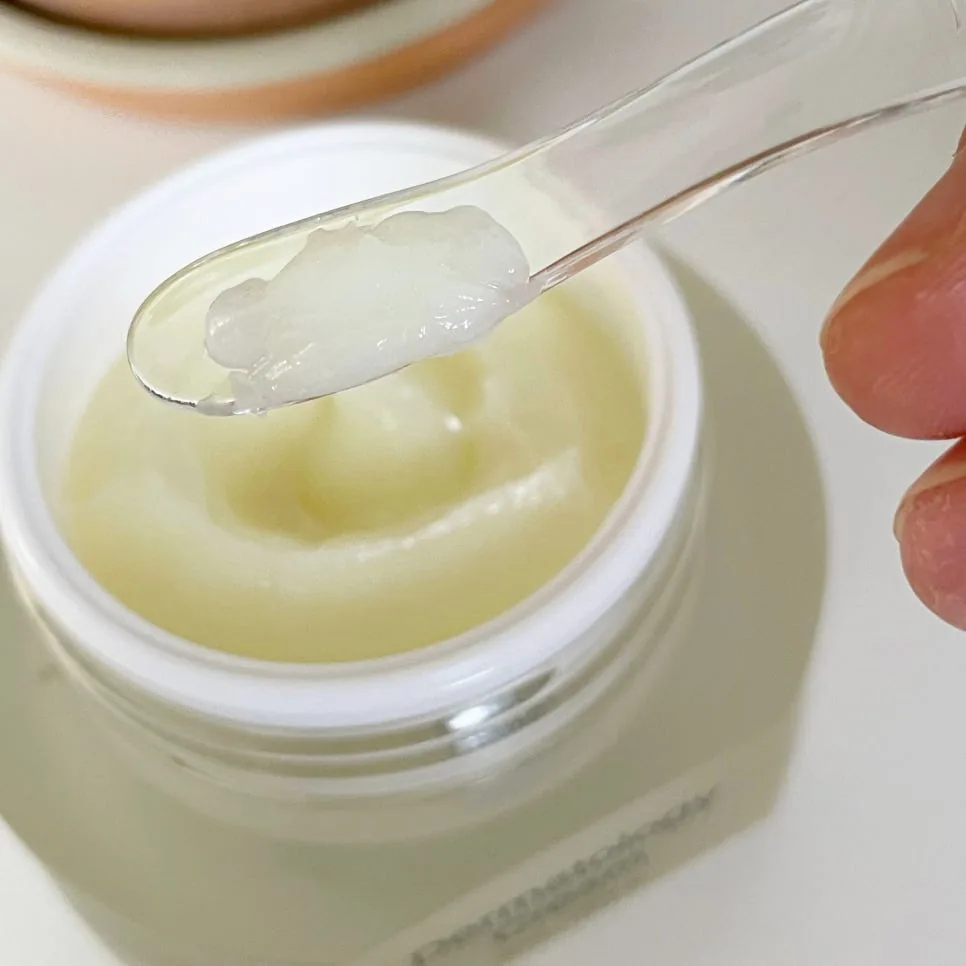 Clear spatula scooping white Dermatology Cream from its open jar