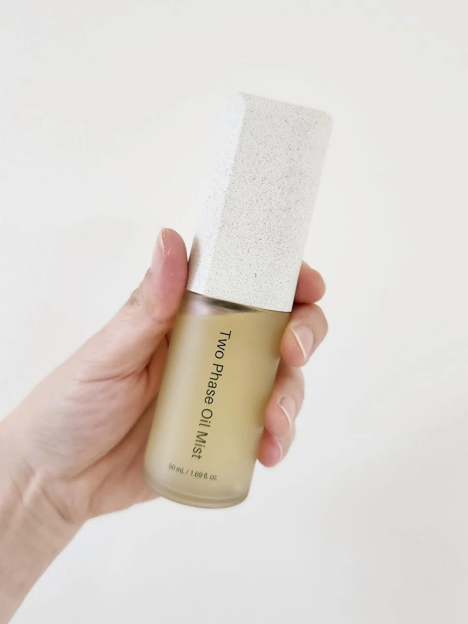 The same bottle after shaking, liquid now an even cloudy pale gold with no visible layers